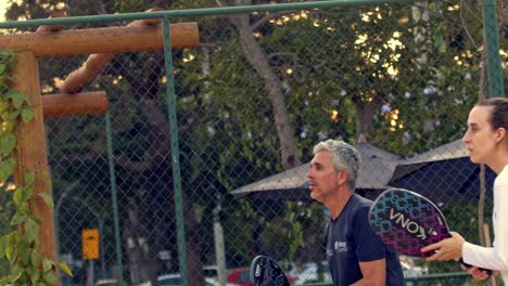 Mixed-couple-playing-and-hitting-a-backhand-shot-in-a-beach-tennis-match