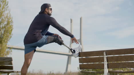 Fit-man-with-disability-putting-foot-on-bench-and-stretching-it
