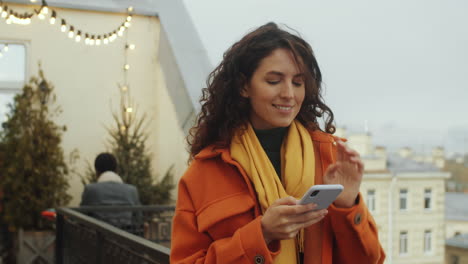 Woman-Using-Phone-and-Enjoying-View-from-Rooftop-Terrace