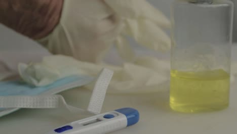 Hand-putting-on-hygienic-gloves-with-medical-supplies-background-close-up-shot