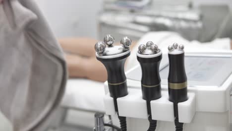 Bokeh-shot-of-electronic-massagers-with-a-masseuse-preparing-the-patient-in-the-background