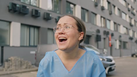 Young-female-wearing-scrub-smiles-and-cheers-outdoor