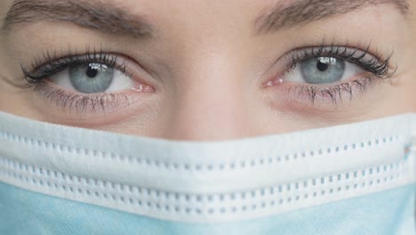 A-woman-in-a-PPE-mask-looks-around-in-extreme-closeup
