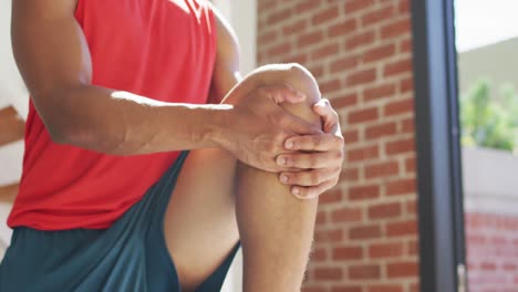 Fit-african-american-man-exercising-at-home-and-doing-stretching-at-home